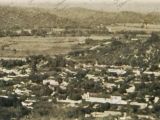 Al fondo y al centro, Carretera Nacional en la Guarenas del año 1915. Ésta conducía a la Hacienda Trapichito, en cuyos terrenos sería construido en 1959 el Grupo Escolar "Ambrosio Plaza". En la parte inferior se observa la Iglesia La Candelaria.