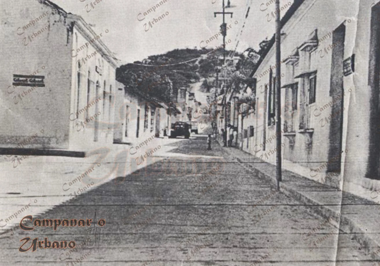Calle Bolívar de Guarenas, década de 1950, siendo utilizada en sentido sur para ascender longitudinalmente el Pueblo Arriba. Se observa la esquina de la calle Colón. La calle Bolívar se considera la calle prima de Guarenas.